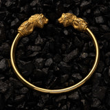 Gold bracelet with lion head designs on a black stone background