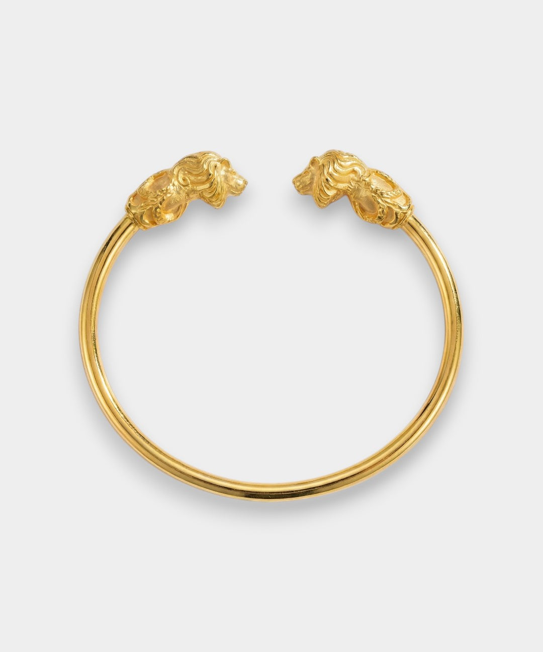 Gold bracelet with lion head clasps on a light gray background