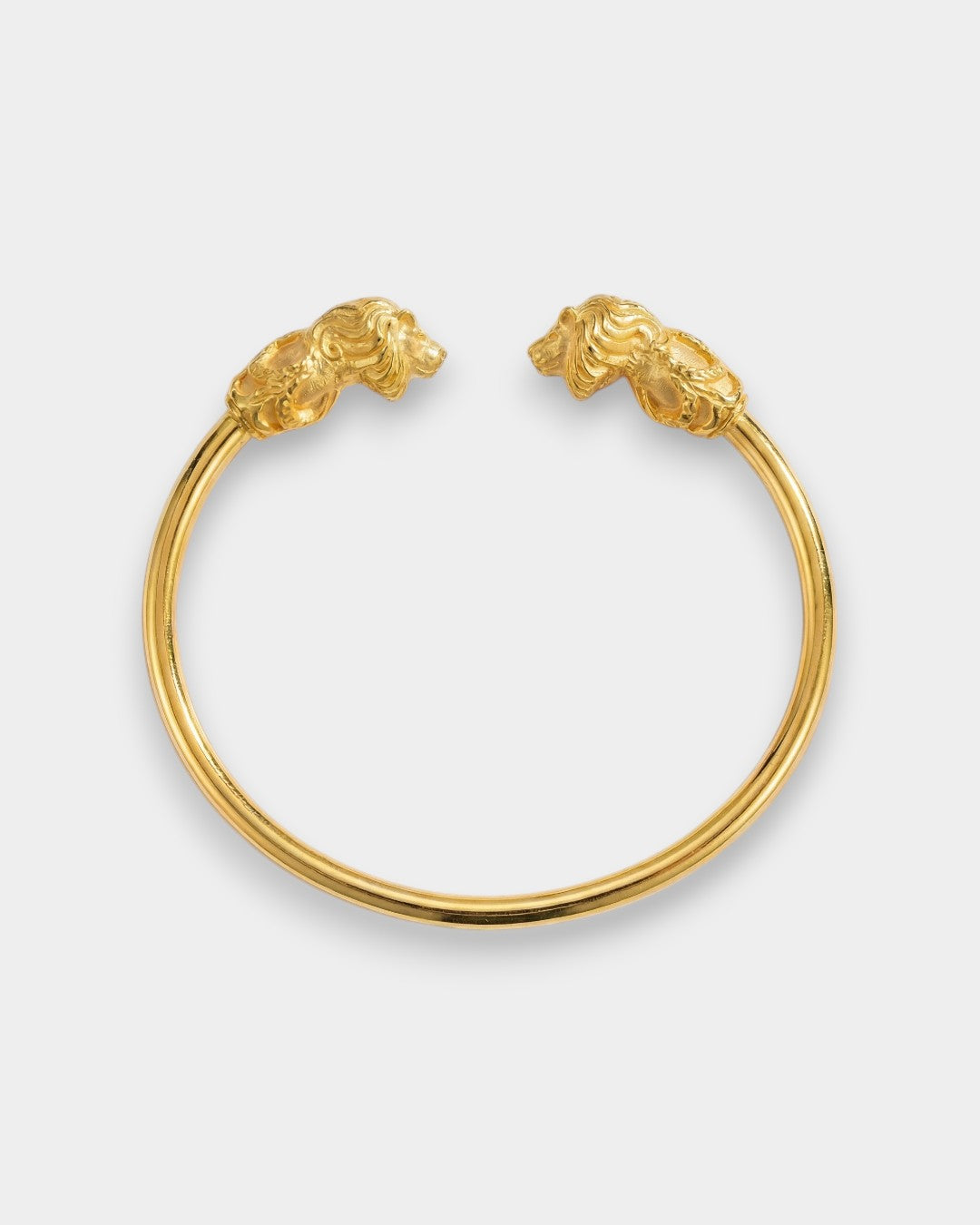 Gold bracelet with lion head clasps on a light gray background