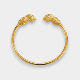 Gold bracelet with lion head clasps on a light gray background