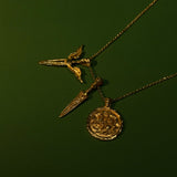 Gold necklace with three pendants on a dark green background
