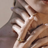 Close-up of a woman's hand wearing a gold snake ring with a delicate band.