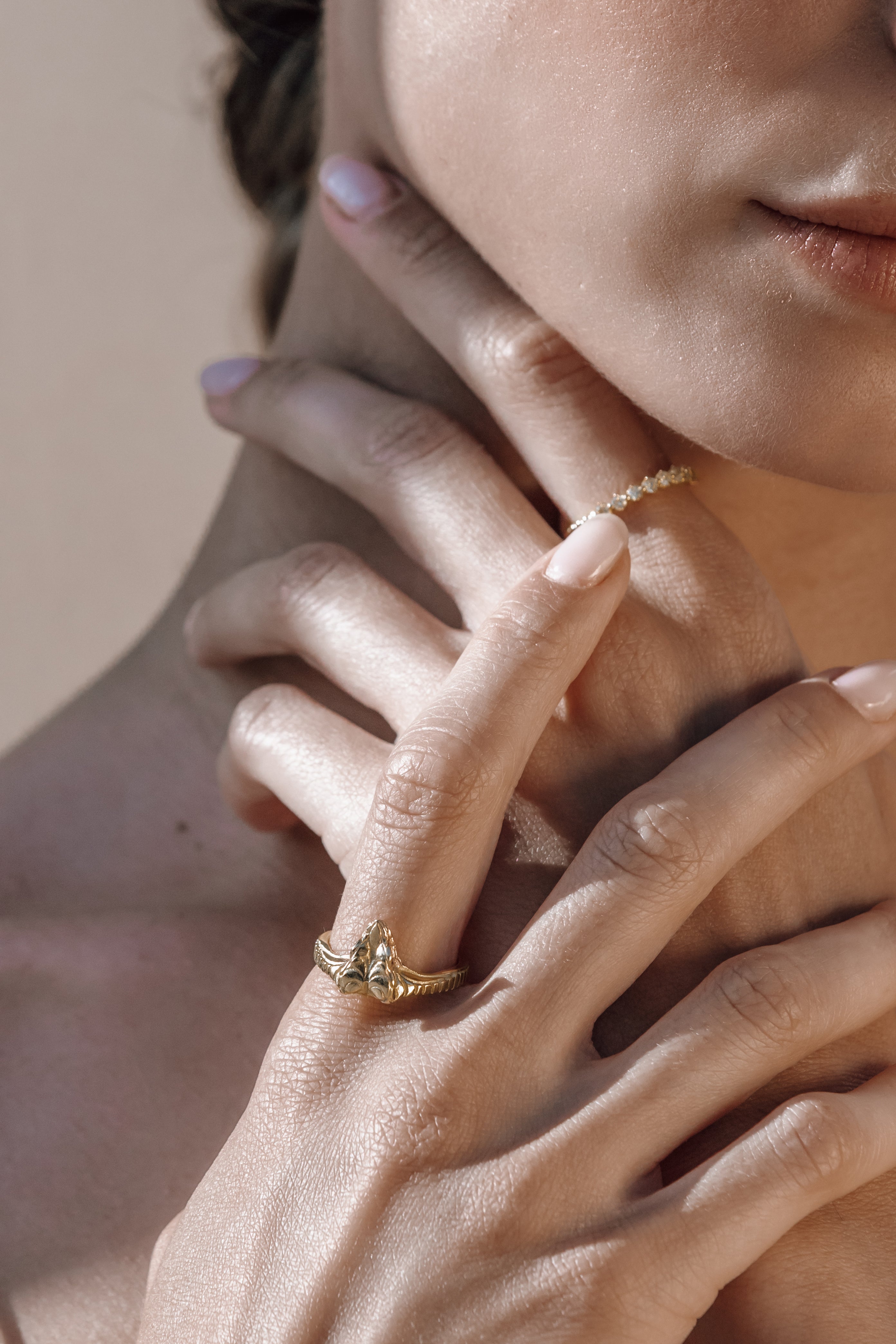 Close-up of a woman's hand wearing a gold snake ring with a delicate band.