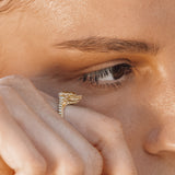 Close-up of a person wearing a gold snake ring on their finger.