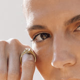 Close-up of a person wearing a gold snake ring on a light background