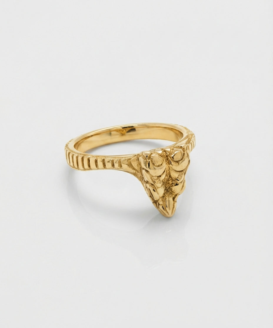 Gold ring with a snake head design on a light gray background