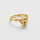 Gold ring with a snake head design on a light gray background