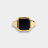 Gold ring with a black stone on a light gray background