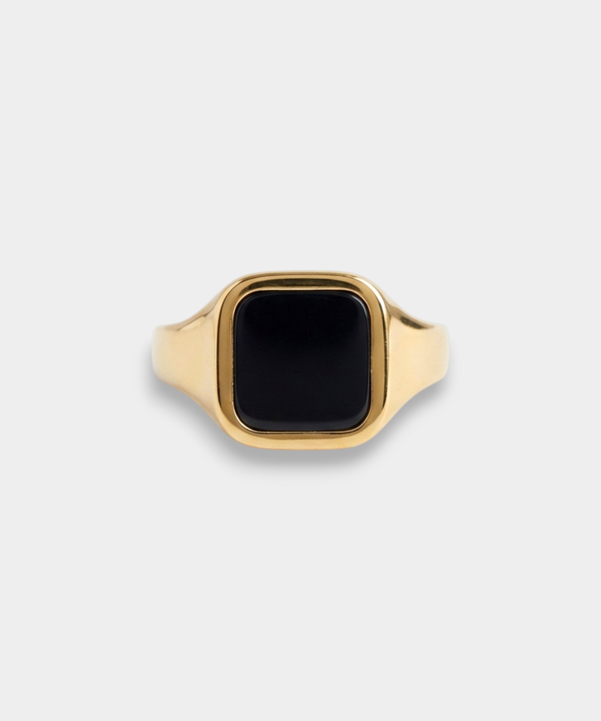 Gold ring with a black stone on a light gray background