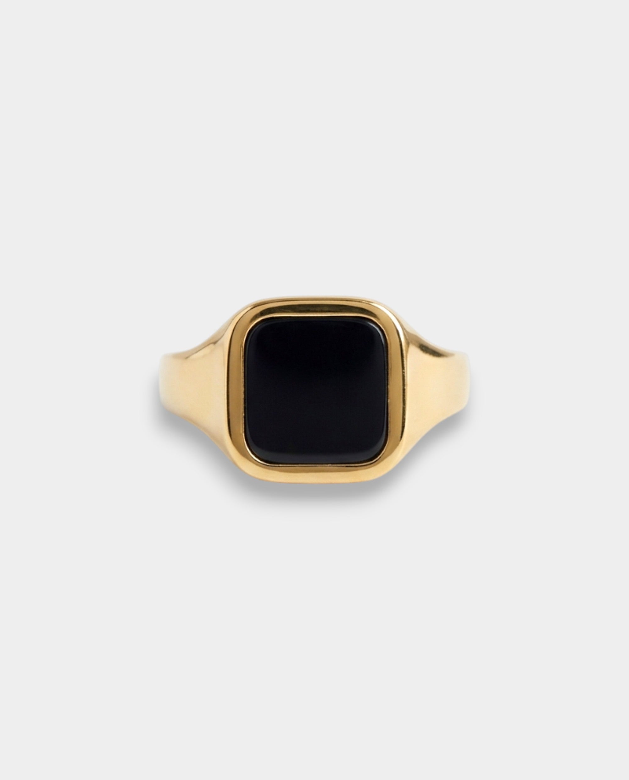 Gold ring with a black stone on a light gray background
