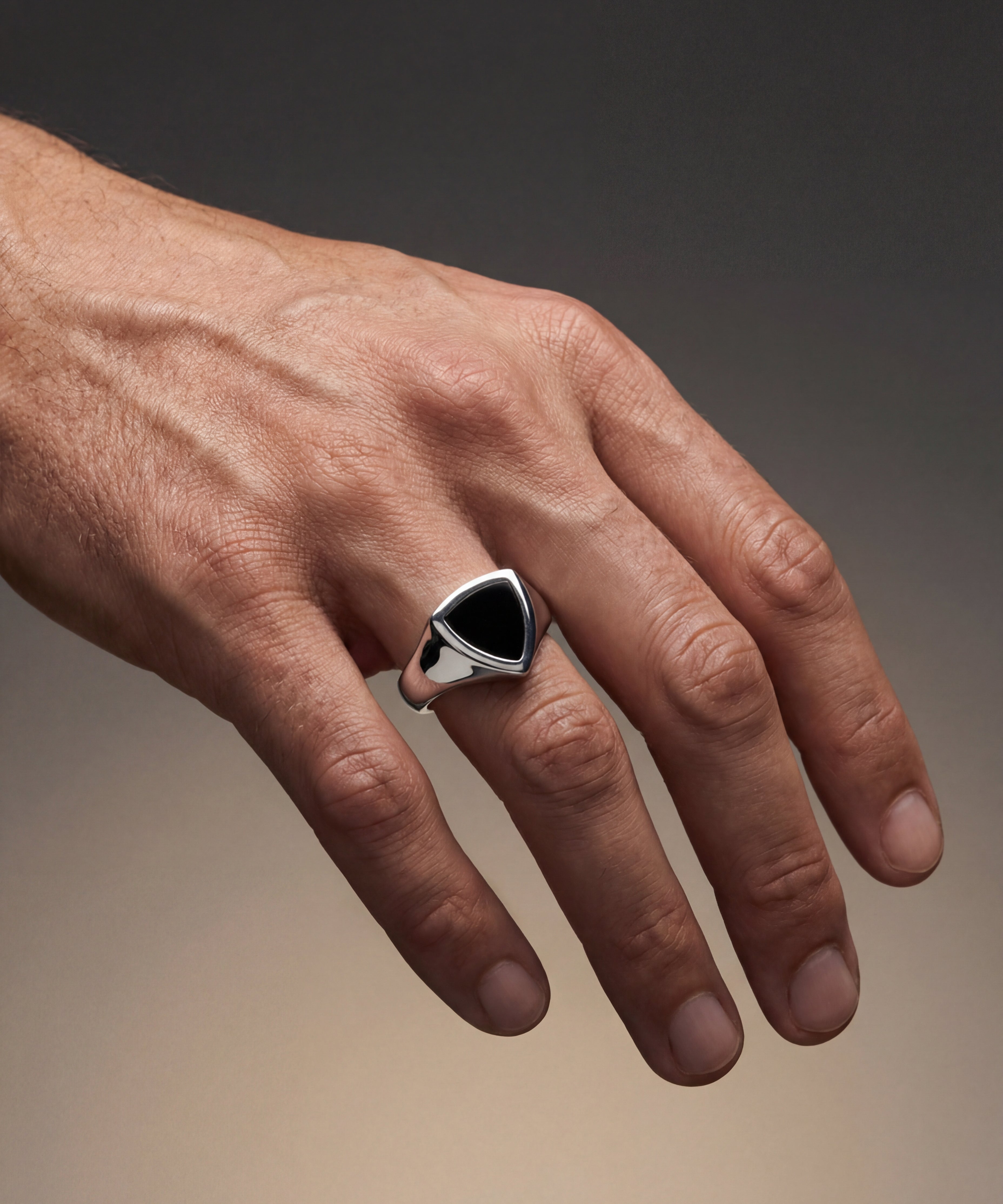 Hand wearing a silver ring with a black stone on a gradient background