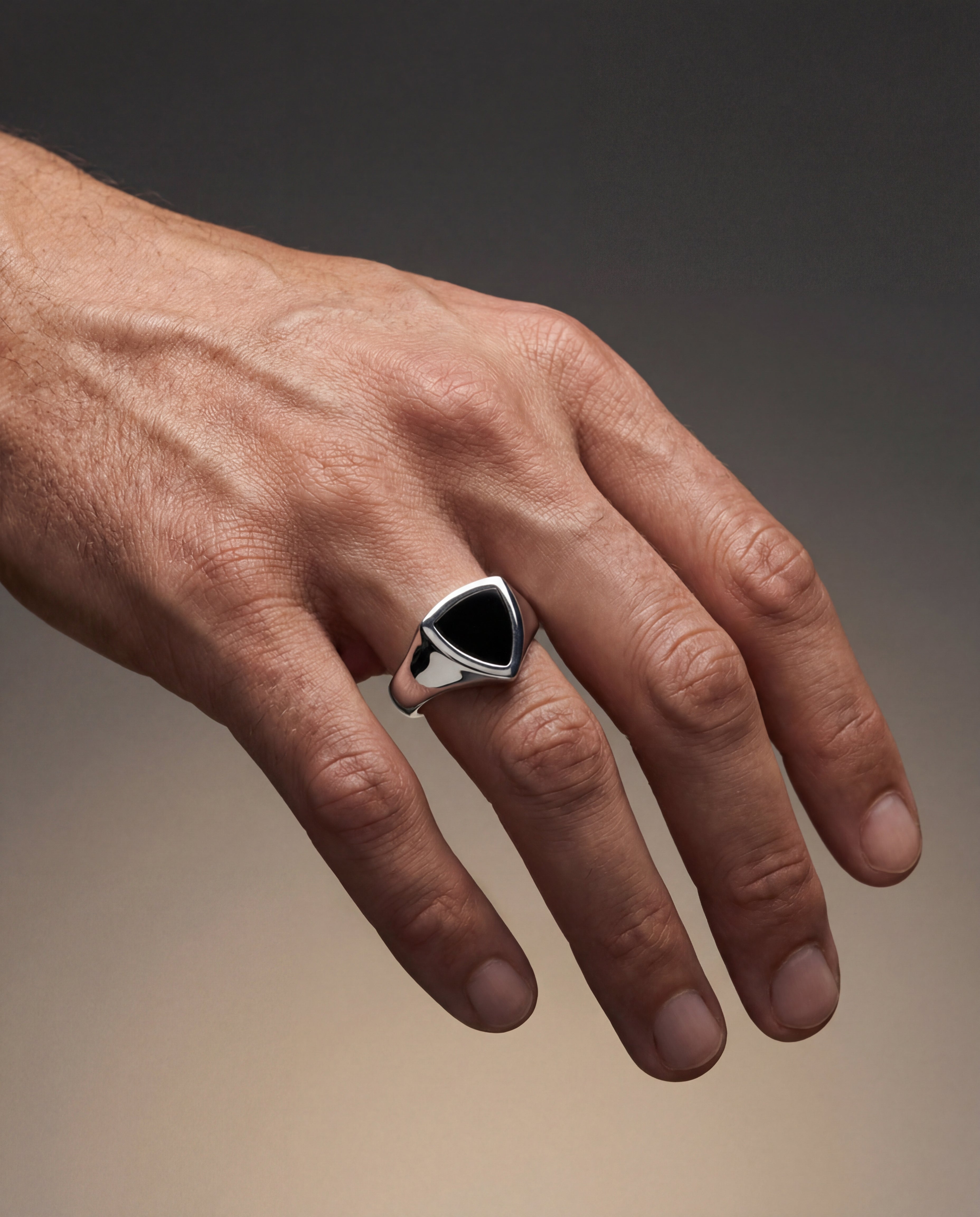 Hand wearing a silver ring with a black stone on a gradient background