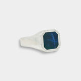 Silver ring with a blue stone on a light gray background