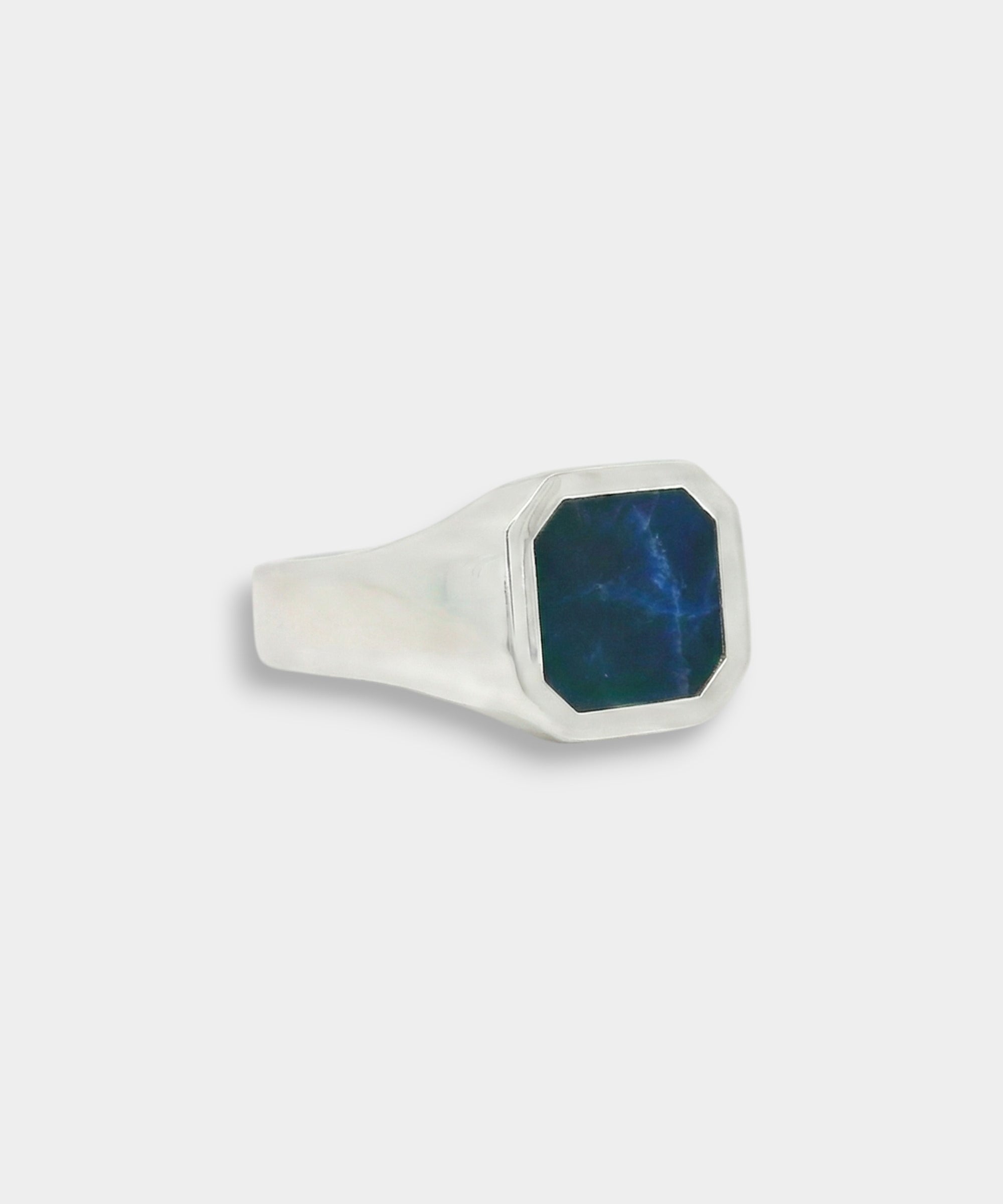 Silver ring with a blue stone on a light gray background