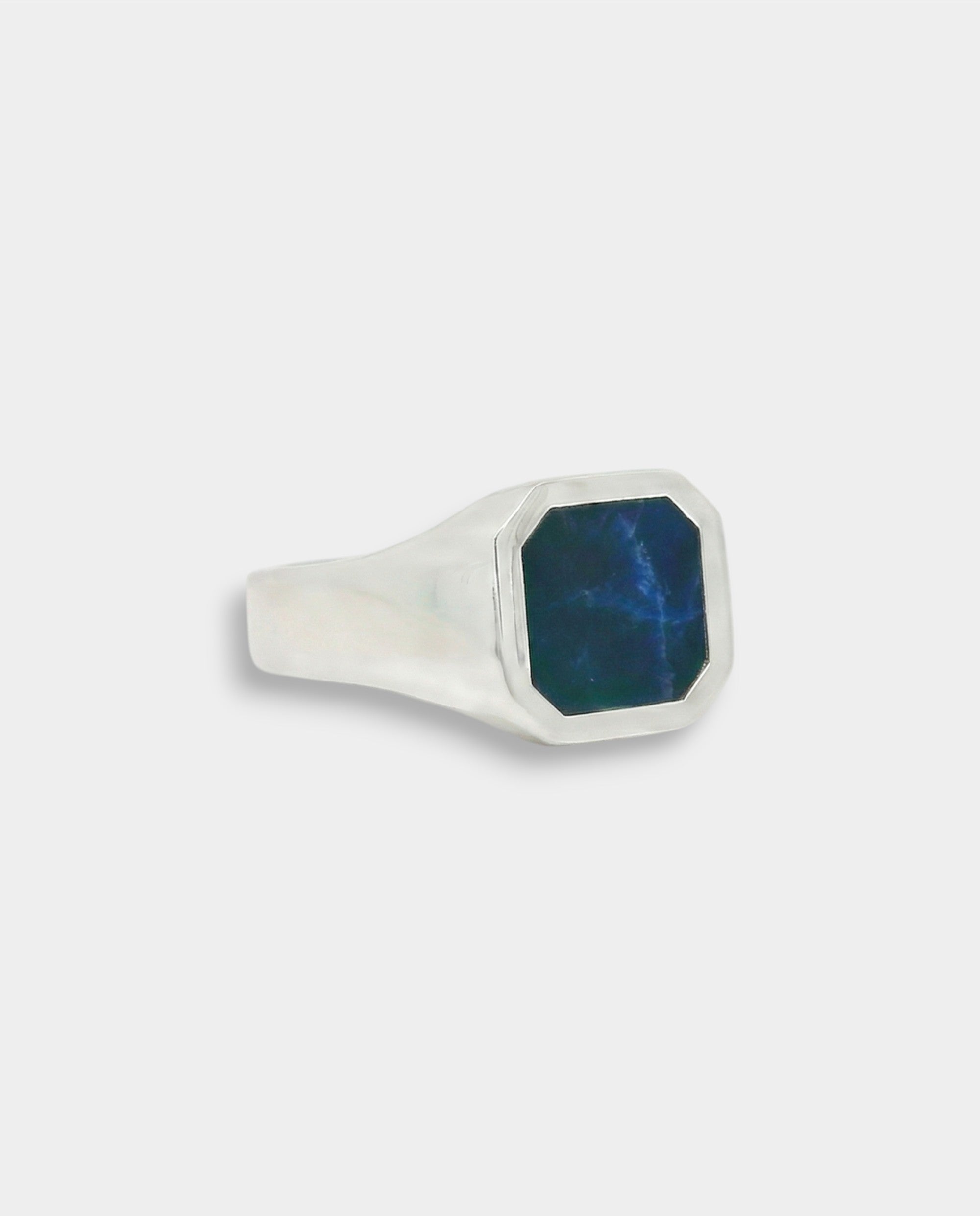Silver ring with a blue stone on a light gray background