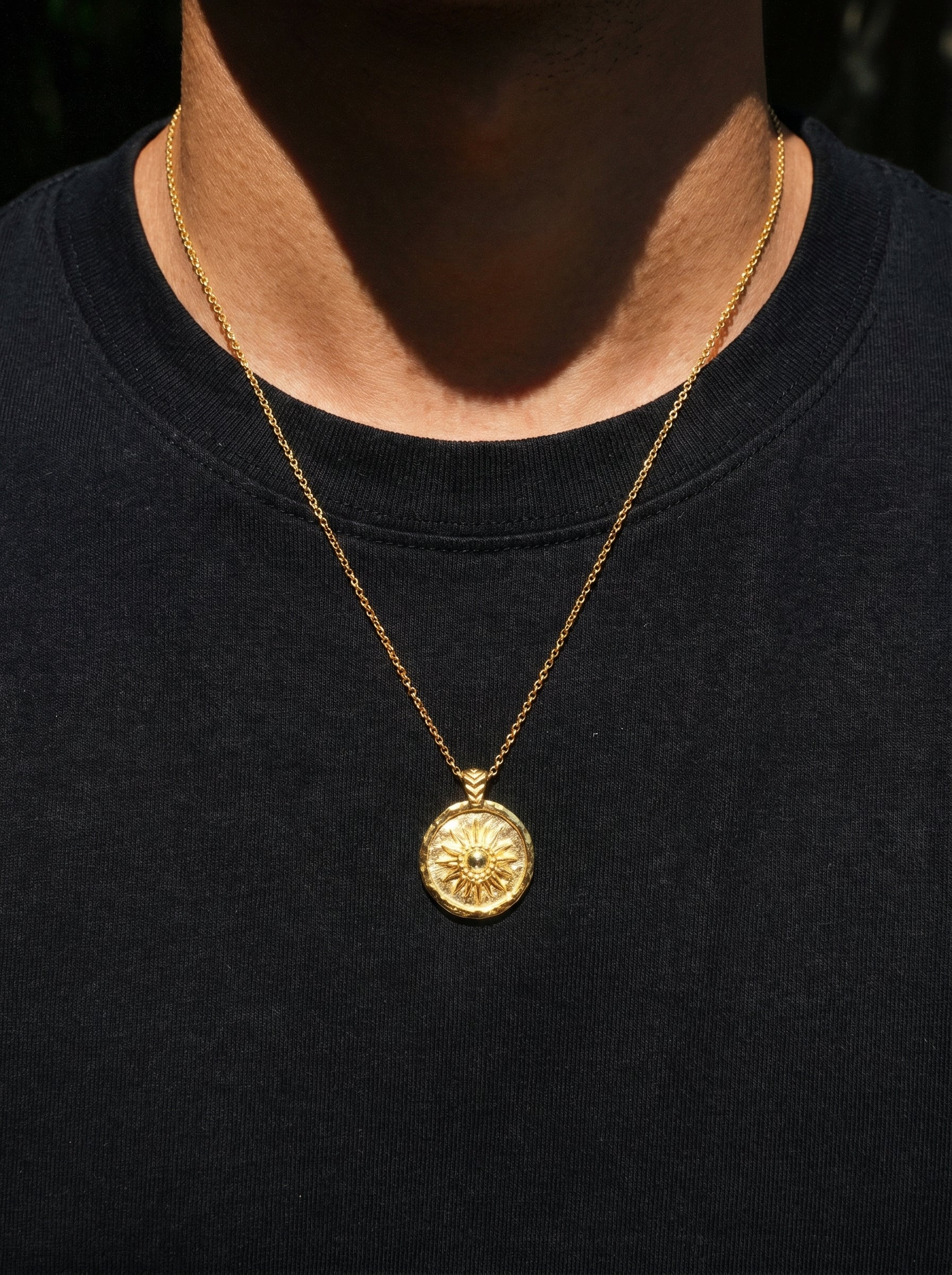 Gold coin necklace with sun image on a black shirt