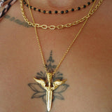 Gold necklace with a unique winged sword pendant on a person's neck with tattoos.