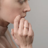 Close-up of a person wearing a ring on a neutral background
