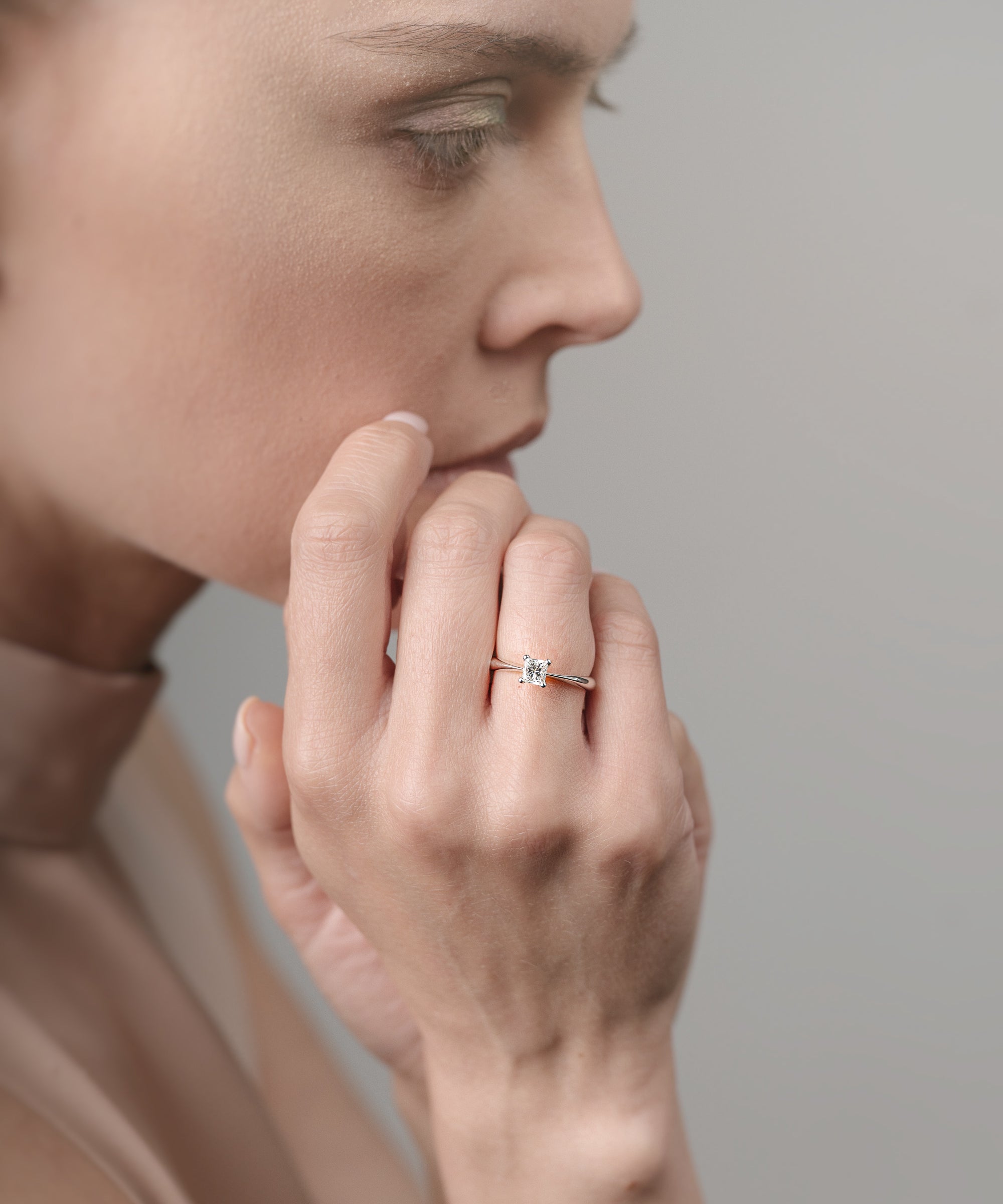 Close-up of a person wearing a ring on a neutral background