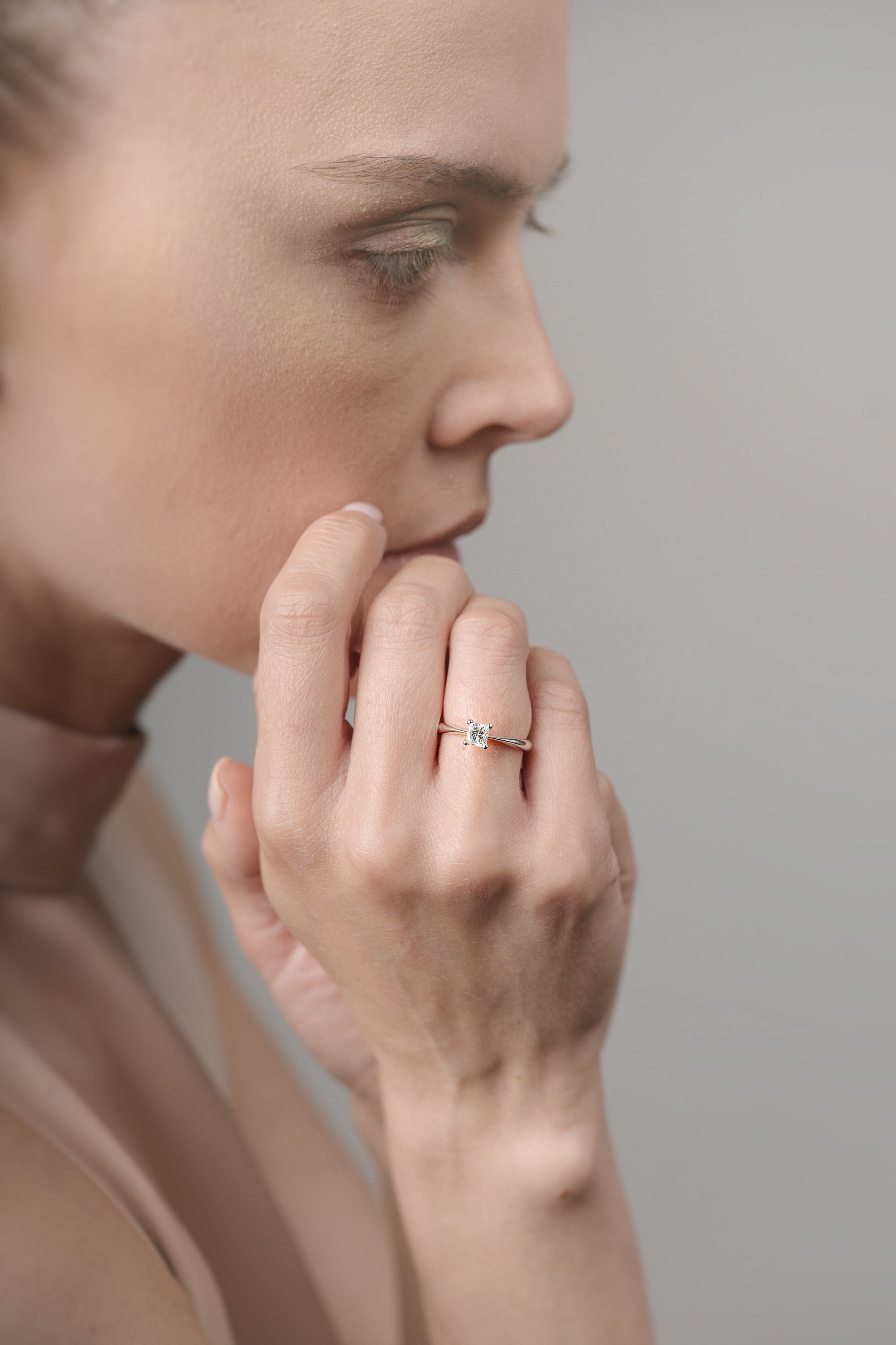Close-up of a person wearing a ring on a neutral background