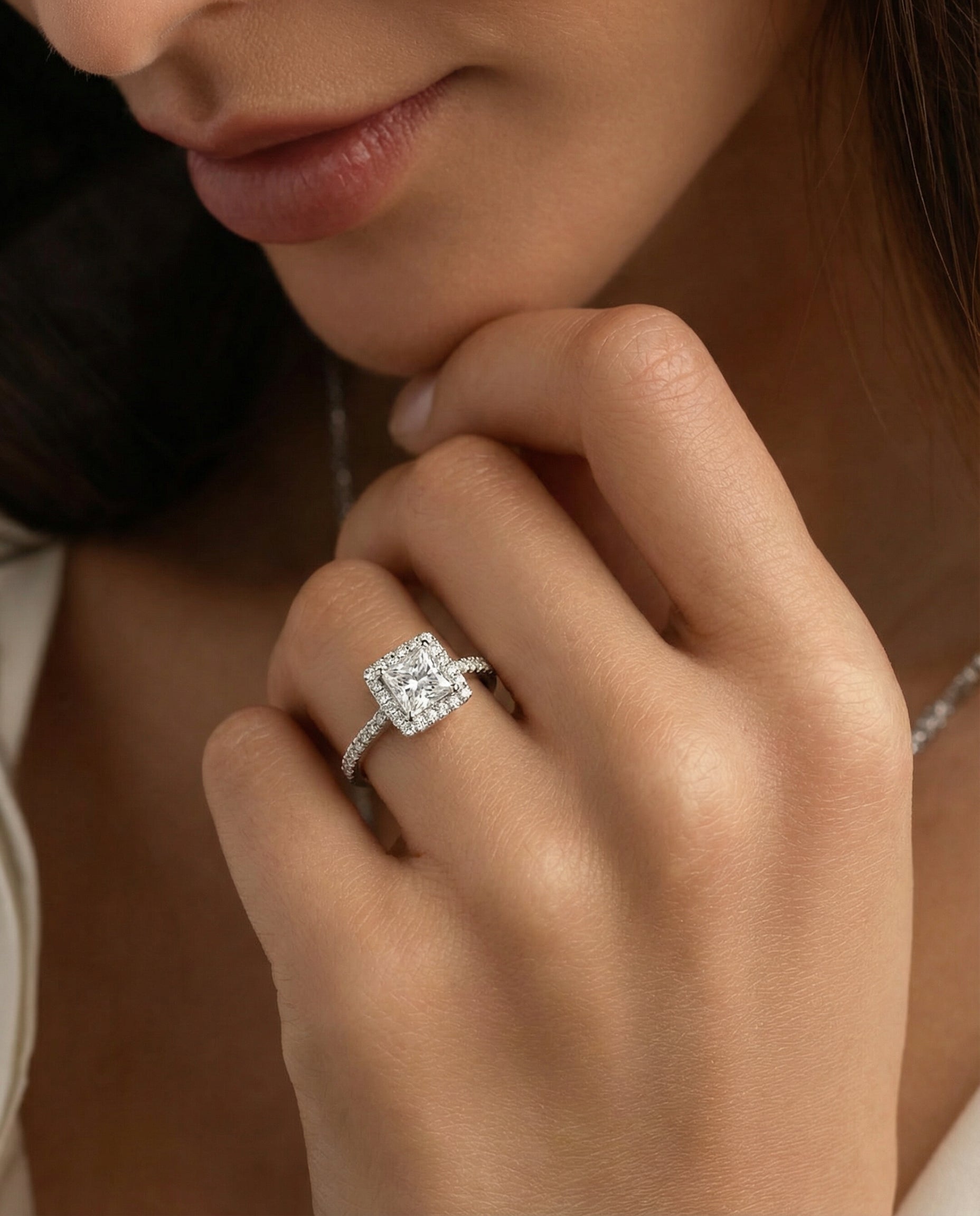 model's hand wearing a princess-cut halo engagement ring