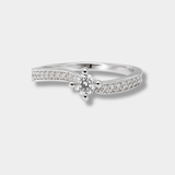 A silver-tone solitaire engagement ring with a round-cut center stone and pavé-set accent stones along the band, shown on a light gray background.