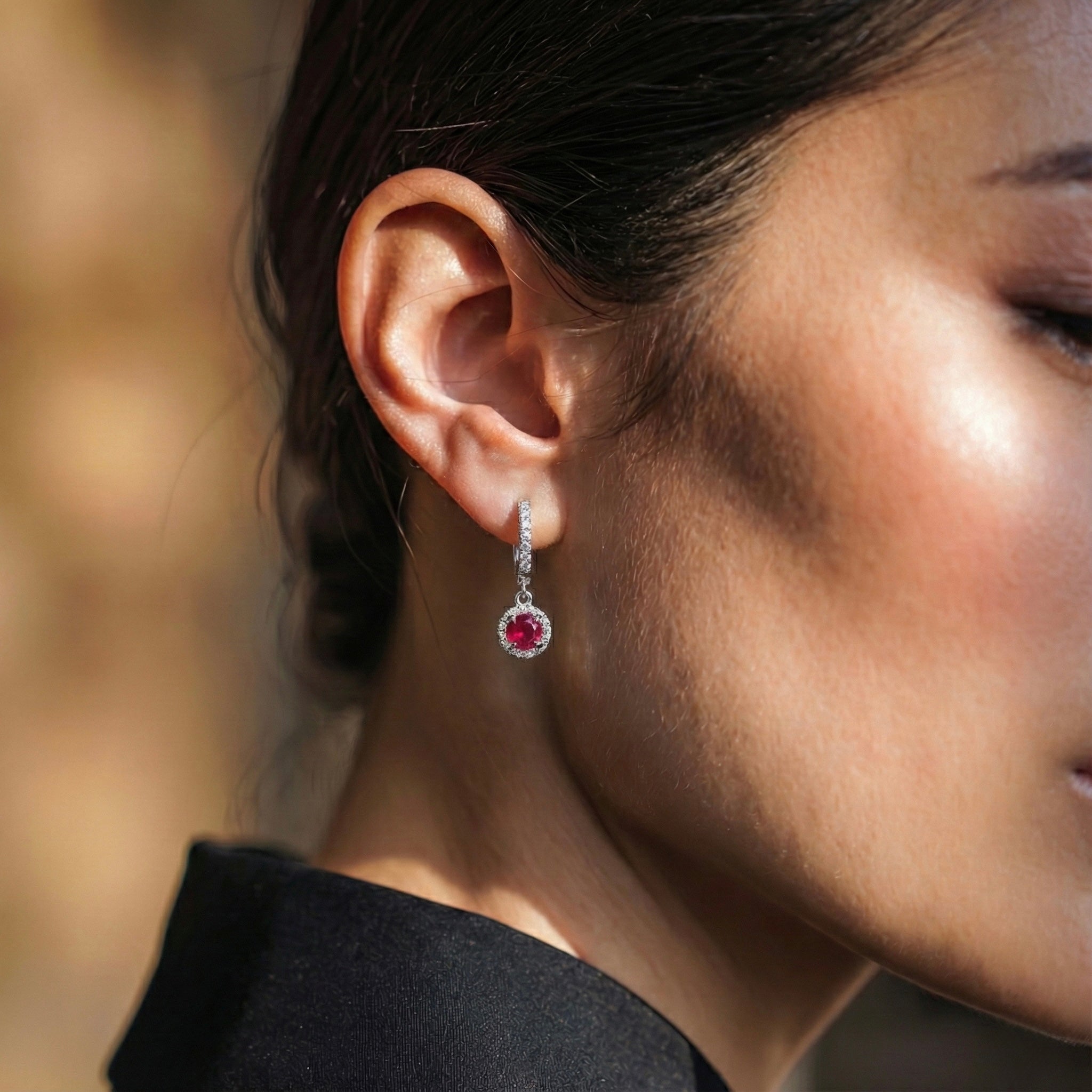 Close-up of a woman wearing a red ruby earring with a blurred background