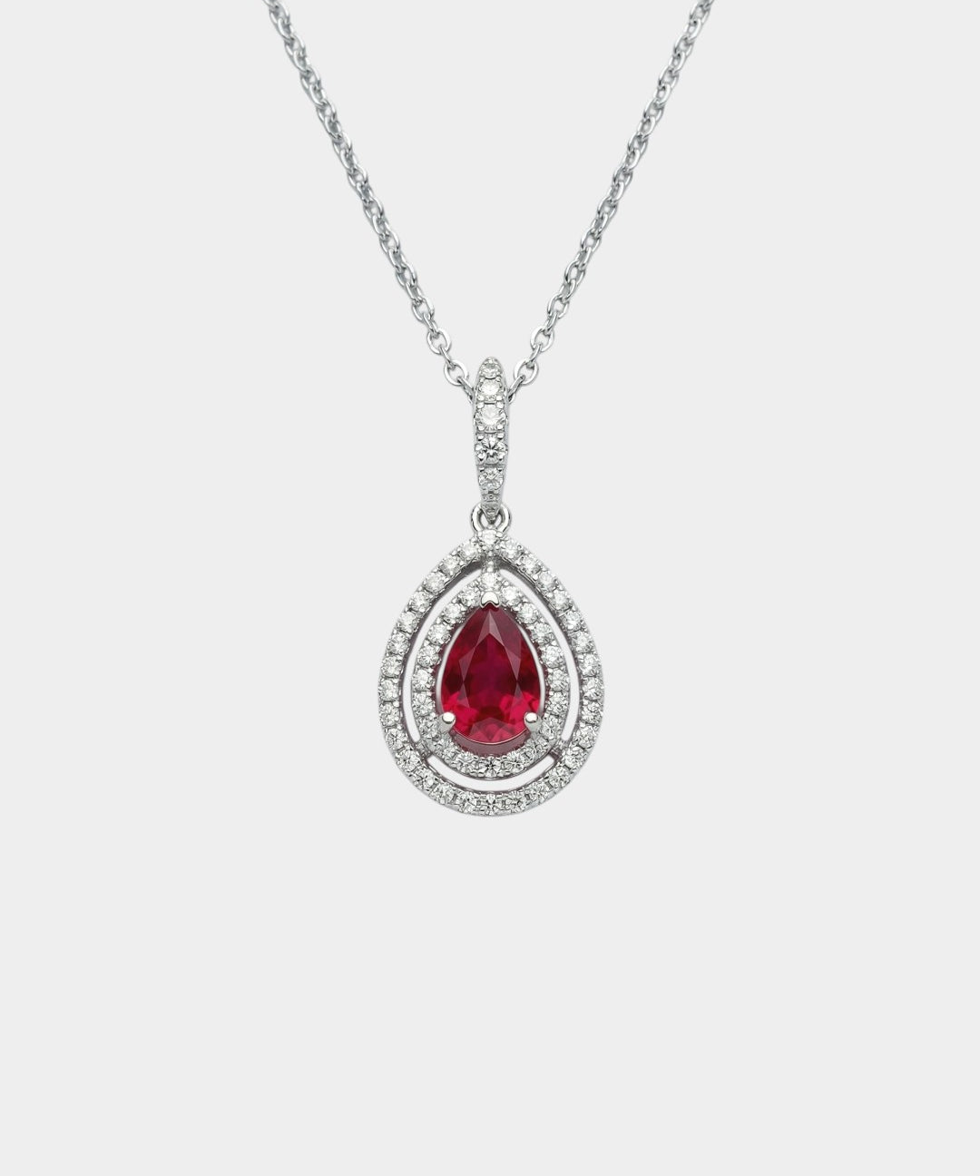 Teardrop-shaped ruby pendant with diamond accents on a white background