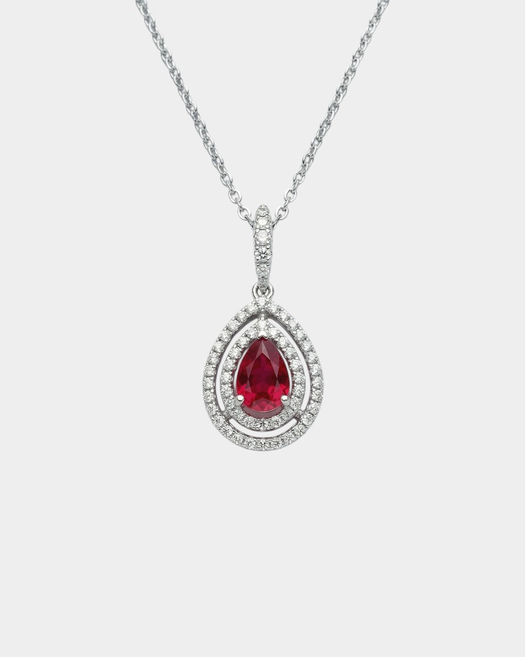 Teardrop-shaped ruby pendant with diamond accents on a white background