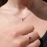 Close-up of a necklace and ring with ruby gemstones on a person's neck and hand.