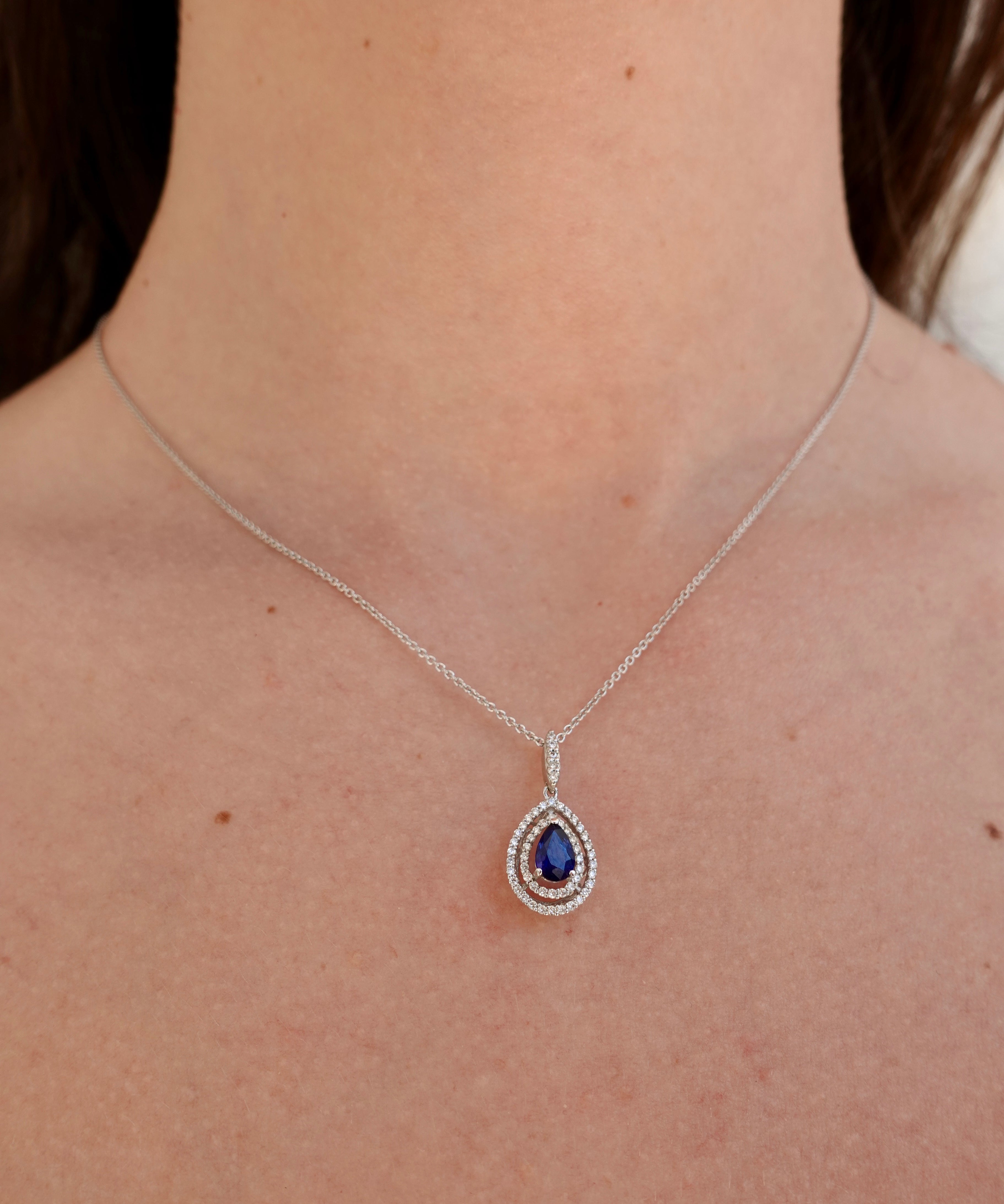 Necklace with a blue sapphire pendant worn by a person