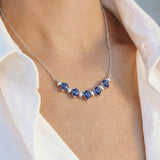 Necklace with blue sapphires worn by a person in a white shirt.