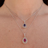 Two white-gold necklaces with gemstone pendants on a person's neck.
