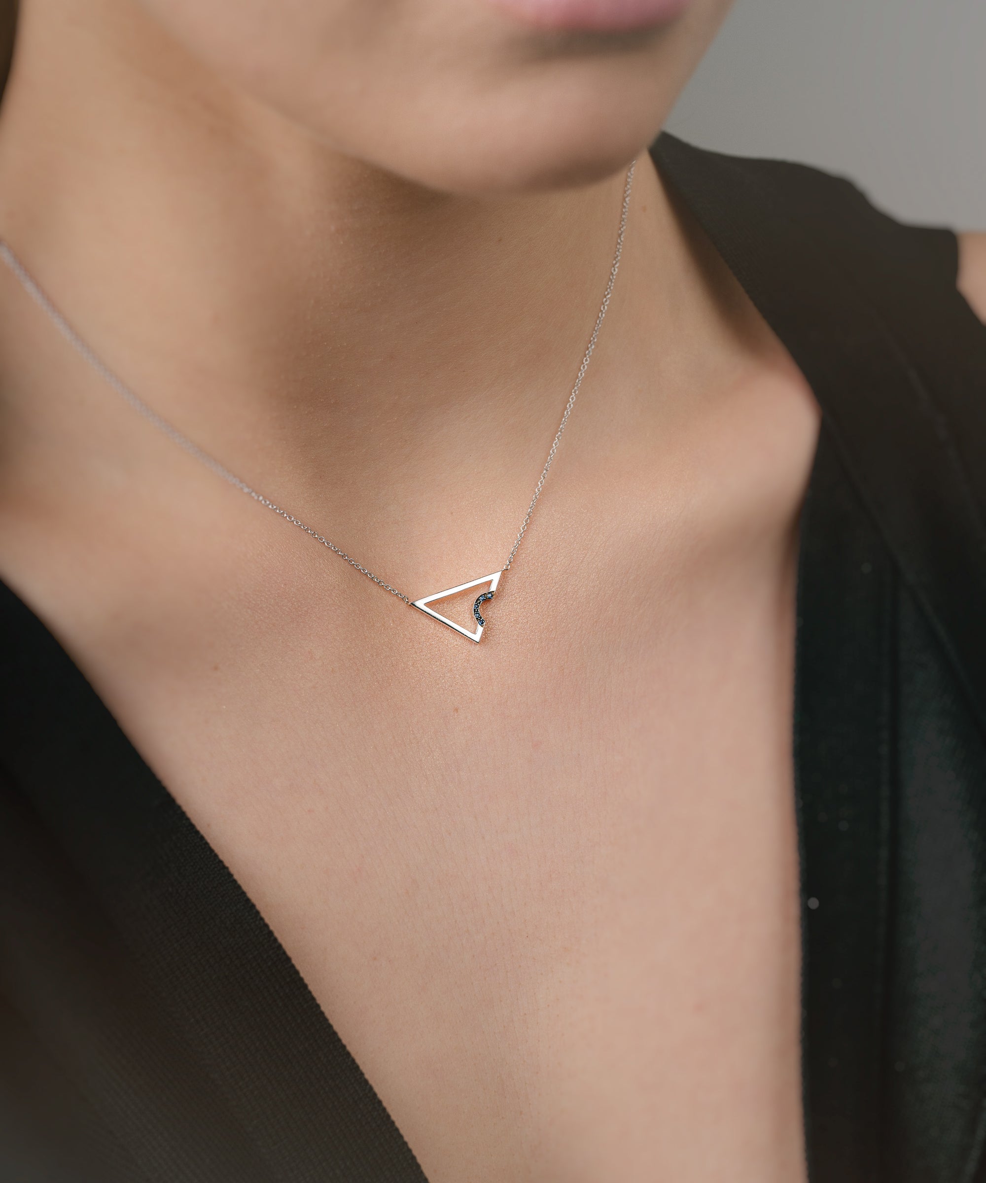 Necklace with a triangle pendant with sapphires worn by a model