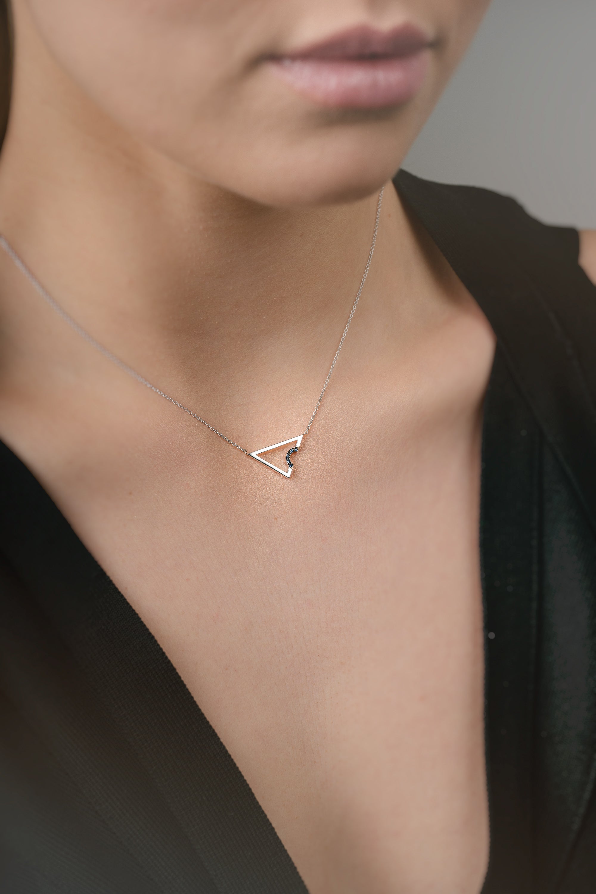 Necklace with a triangle pendant with sapphires worn by a model