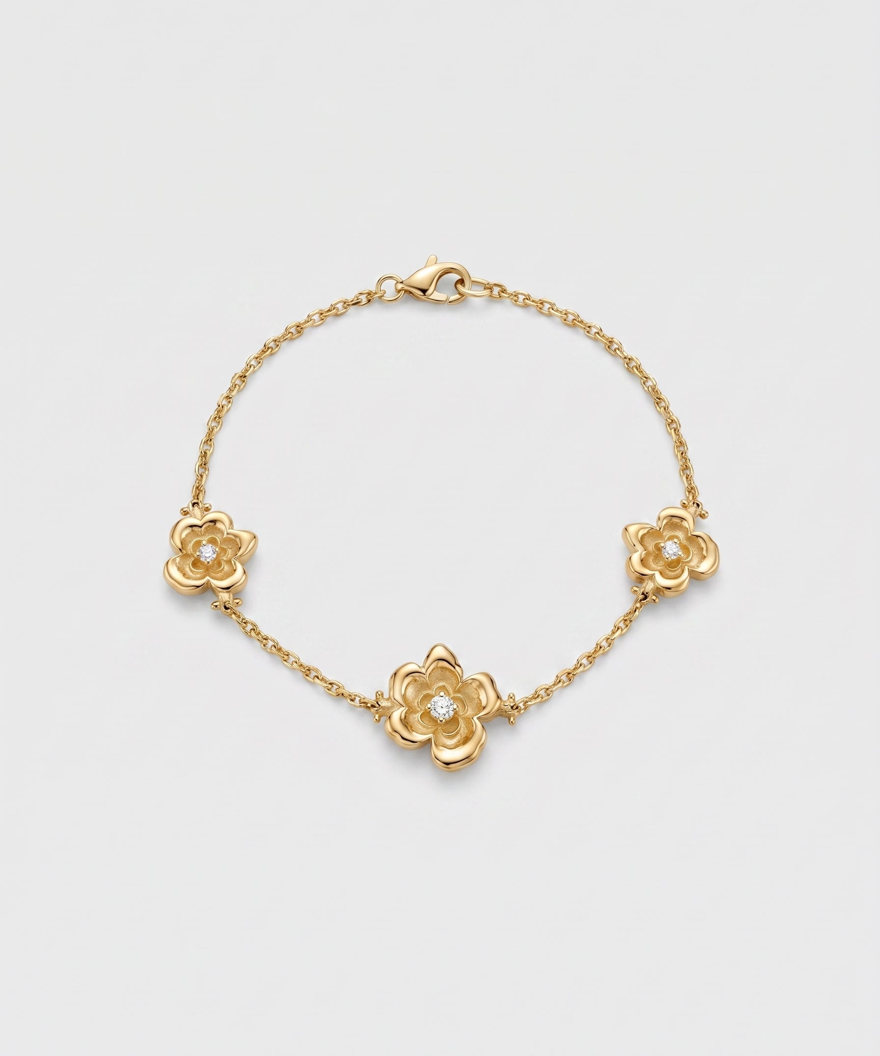 Gold bracelet with three motif floral designs on a light gray background