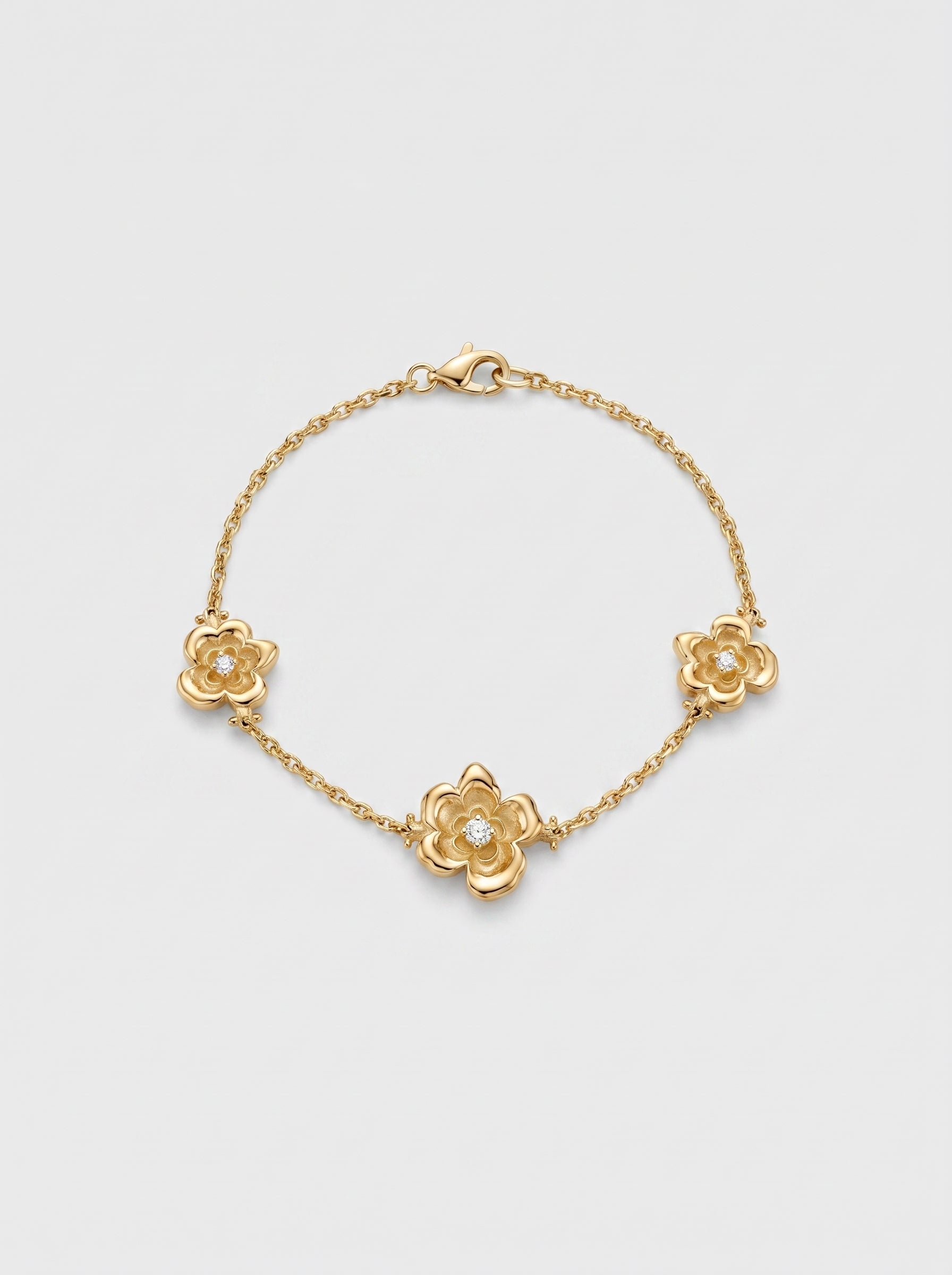 Gold bracelet with three motif floral designs on a light gray background