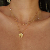 Gold necklace with a floral pendant on a person's neck