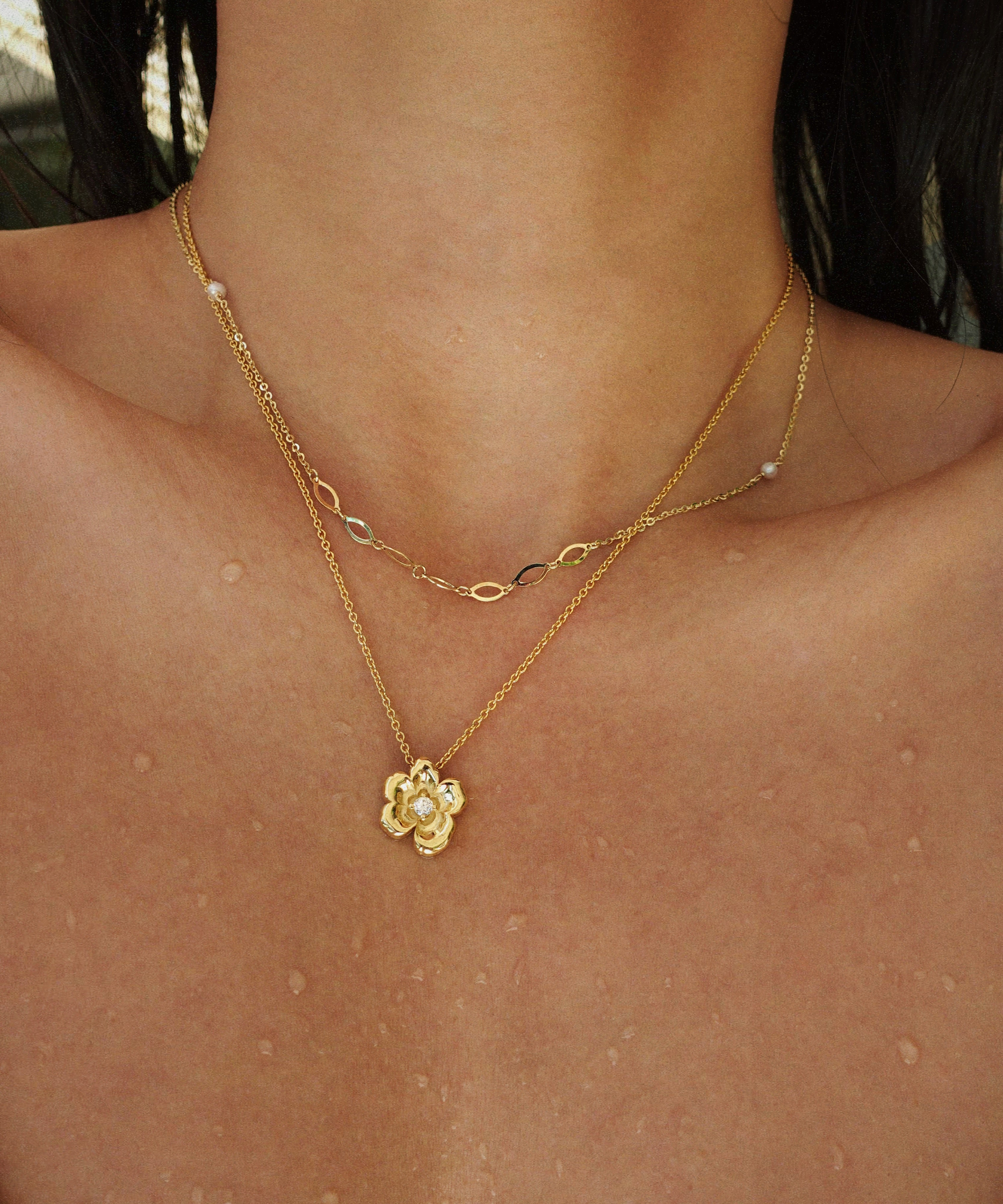 Gold necklace with a floral pendant on a person's neck