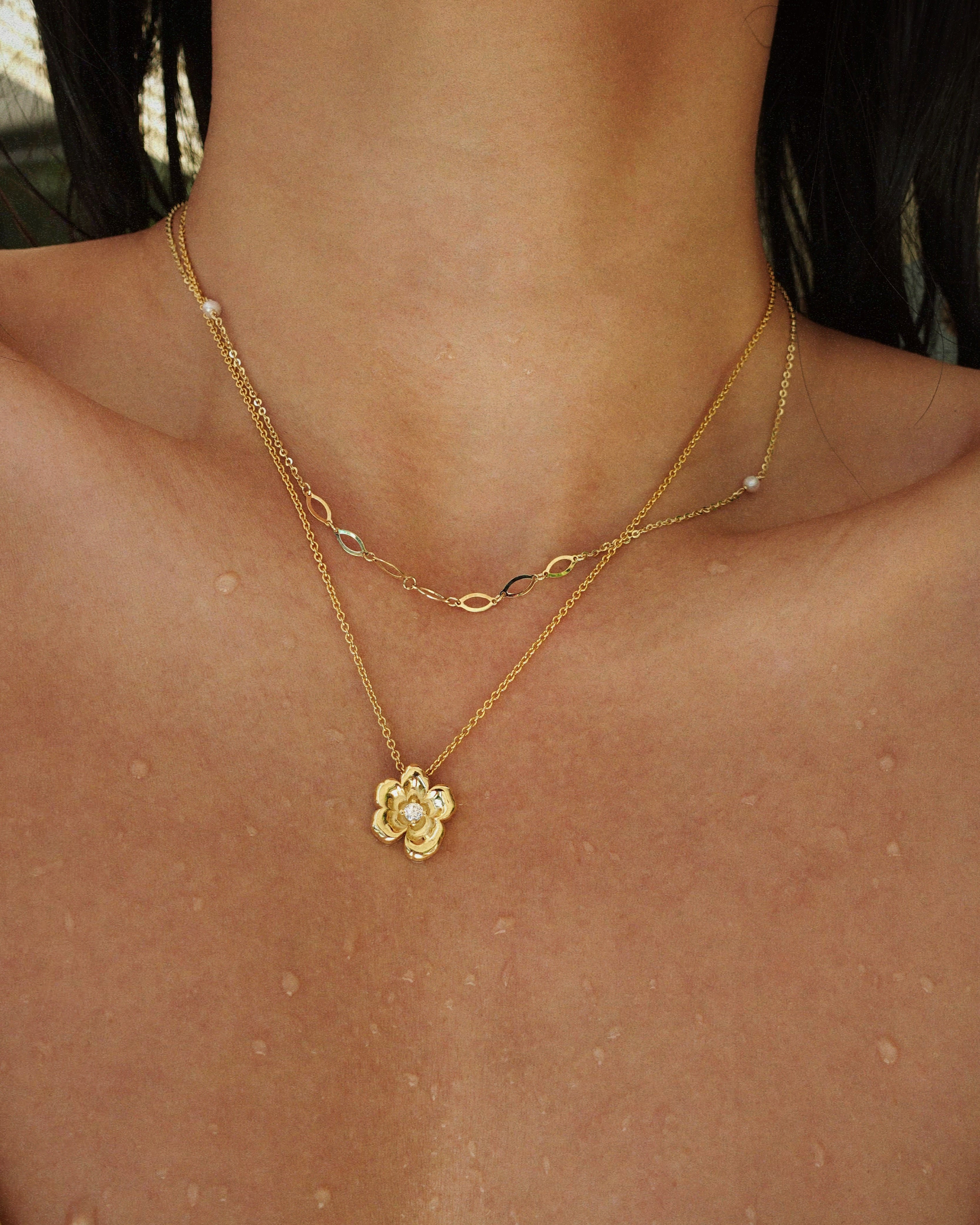 Gold necklace with a floral pendant on a person's neck