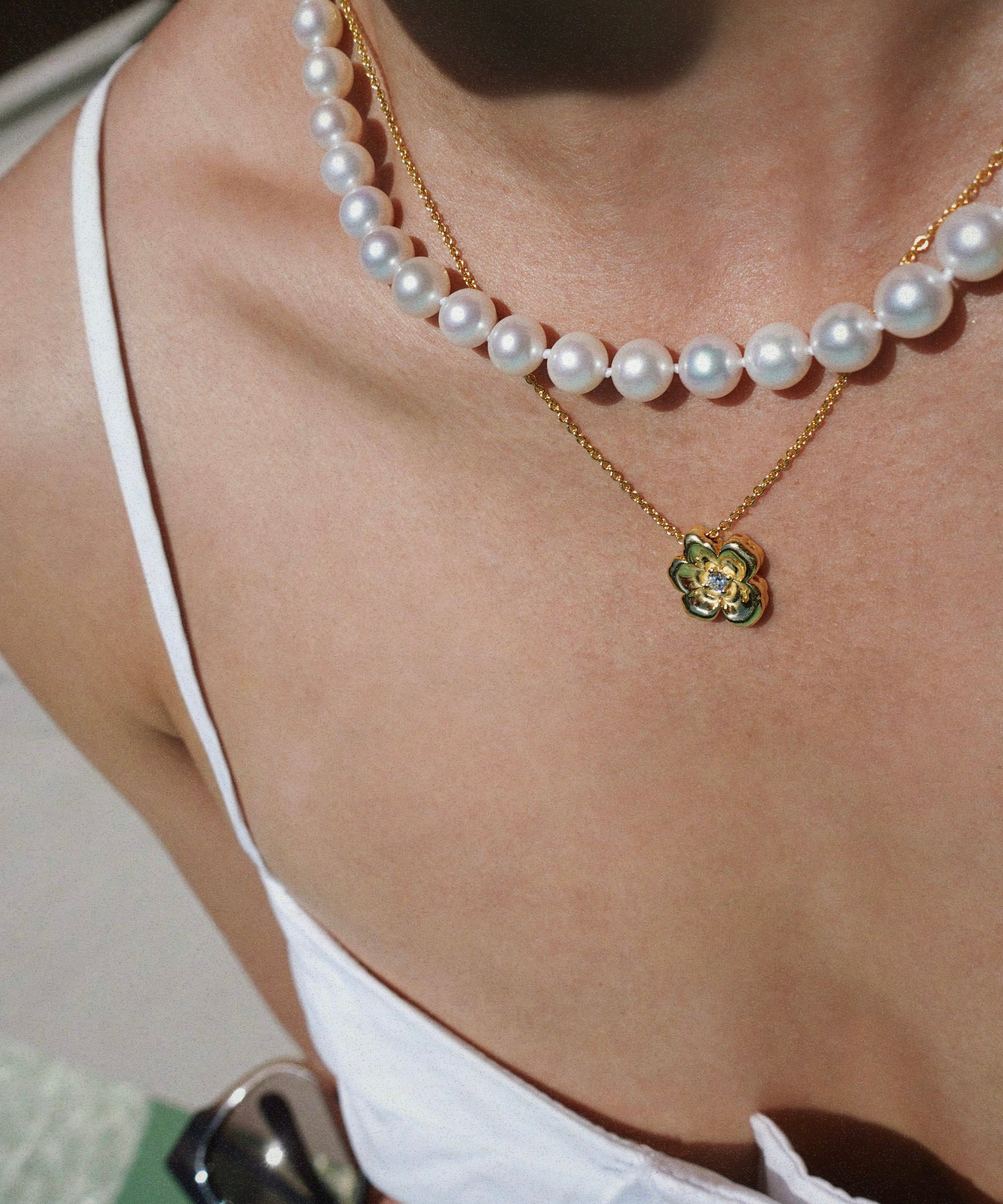 Pearl necklace and a flower pendant worn by a person