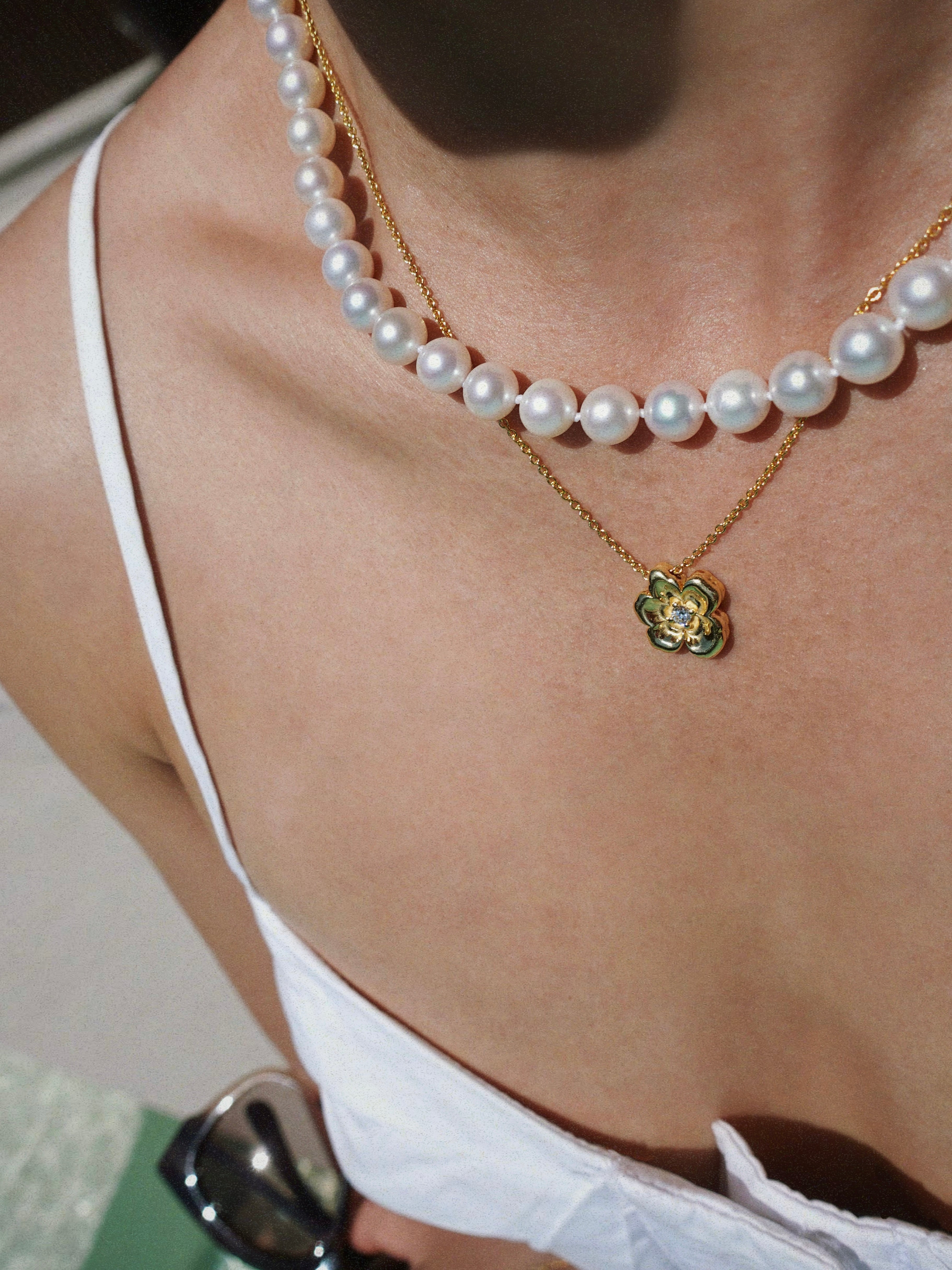 Pearl necklace and a flower pendant worn by a person
