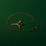 Gold necklace with a unique pendant on a dark green background