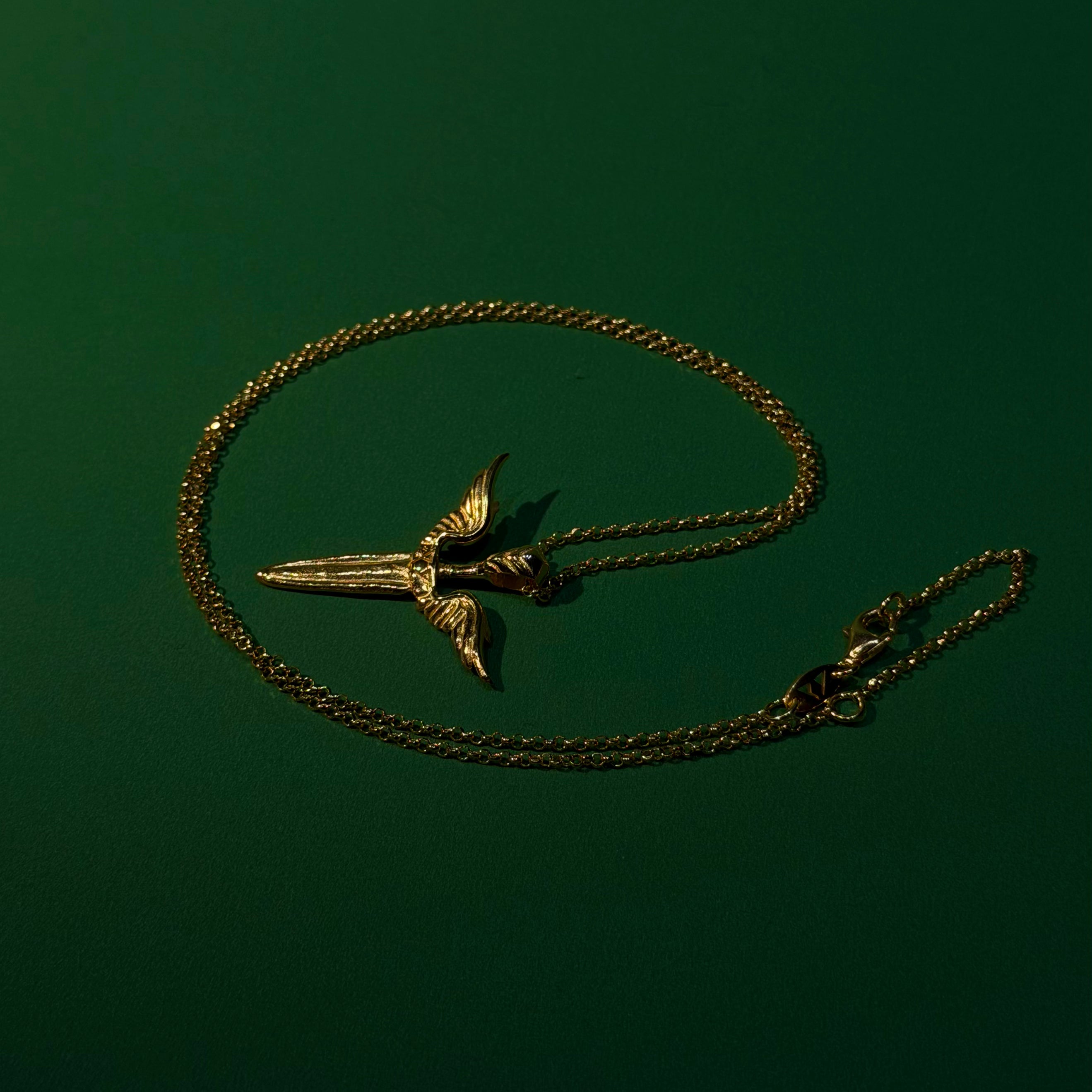 Gold necklace with a unique pendant on a dark green background