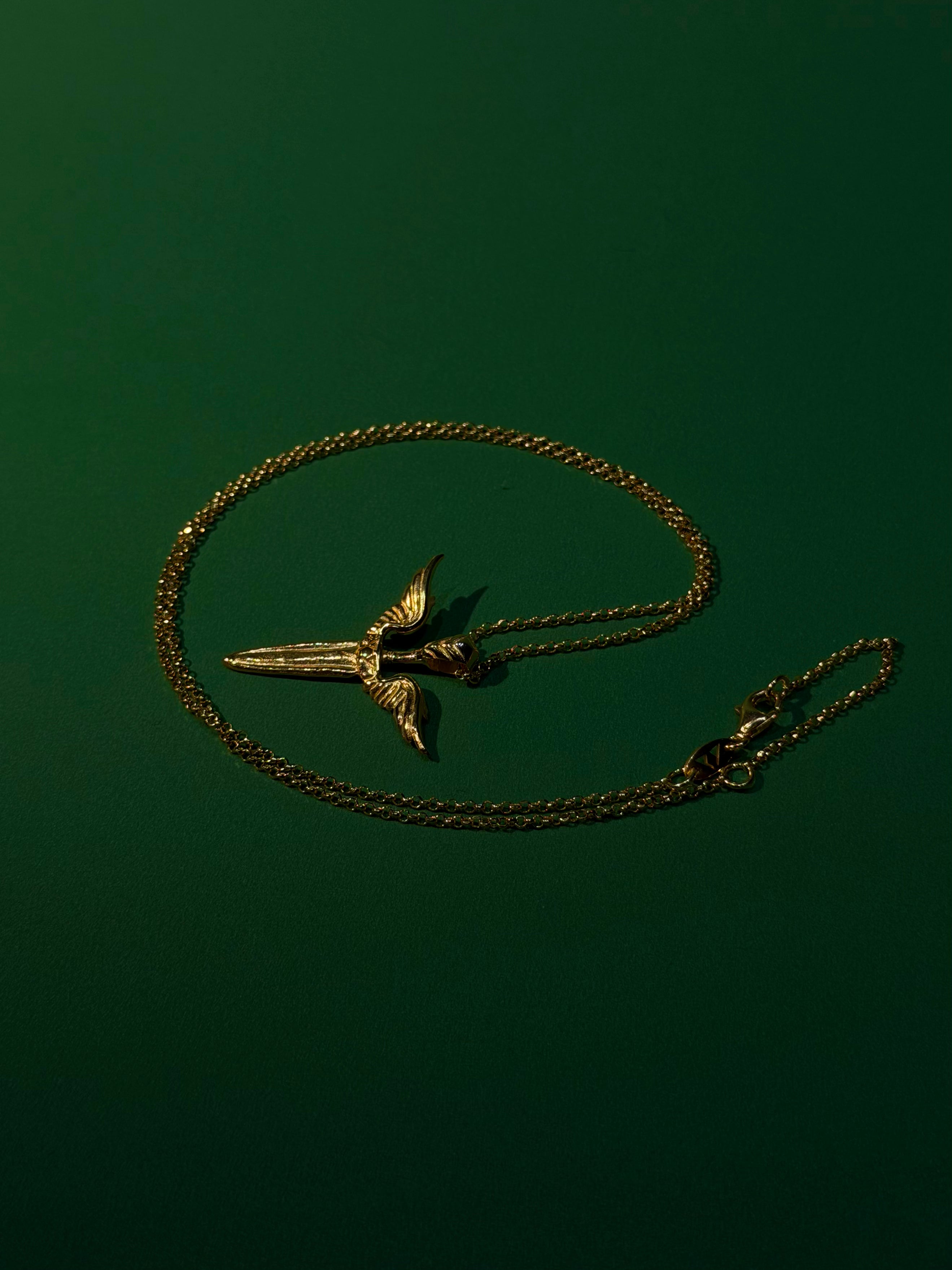 Gold necklace with a unique pendant on a dark green background