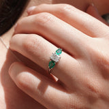 Close-up of a hand wearing an emerald and diamond ring.