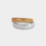 Two rings as one, one gold and one white gold with diamonds, on a light gray background