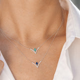 Necklace with blue and green gemstones worn by a person in a white shirt.