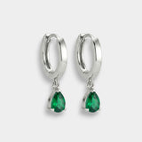 White gold hoop earrings with emeralds on a white background