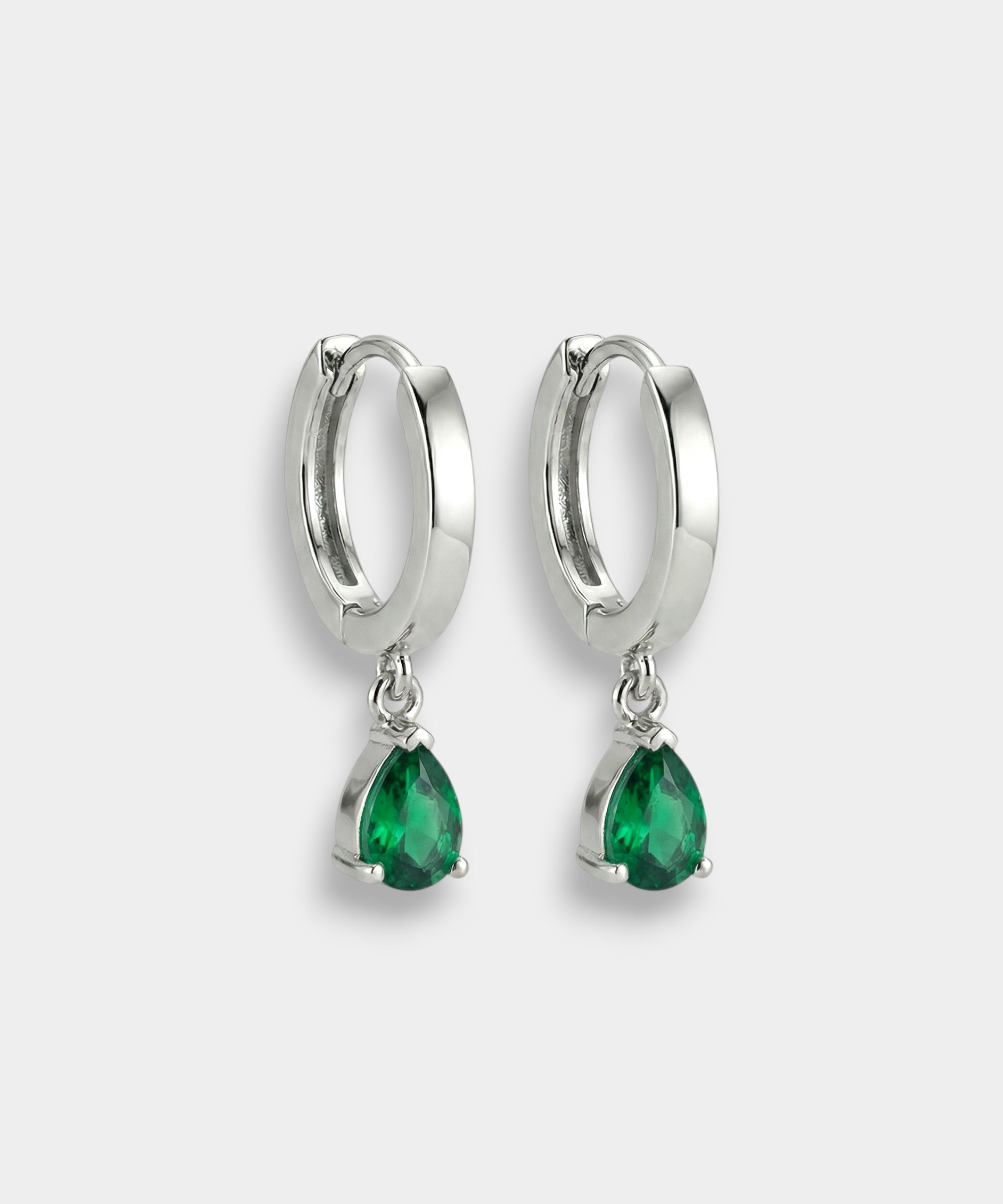 White gold hoop earrings with emeralds on a white background